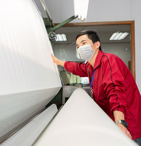 A worker is operating the fabric inspection machine